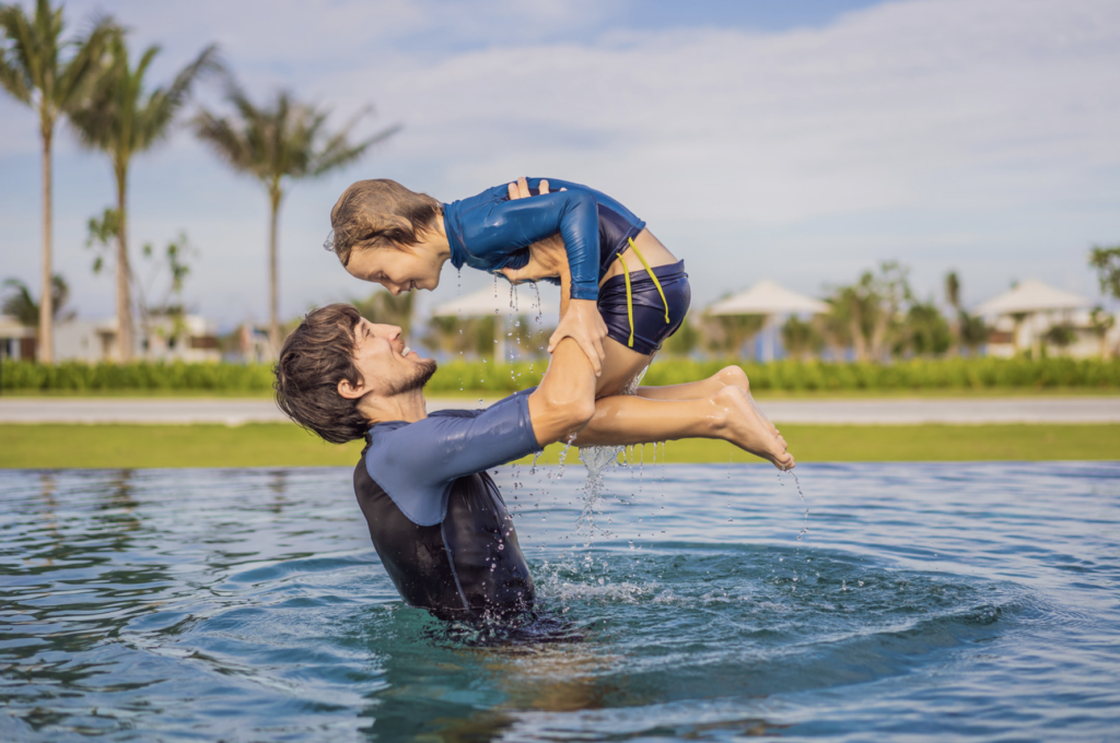This is an image of a father lifting his son in a pool.